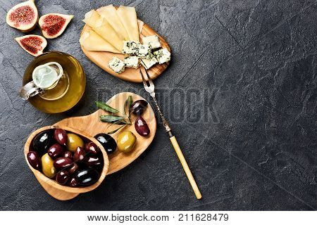 Italian snacks food with Cheese, Olives, Oil and Figs on black concrete background with copy space. Top view. Copy space.