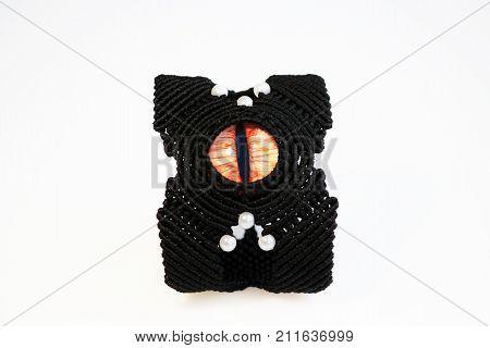 black bracelet for the hand from waxed thread and red dragon eye in the technique of macrame on a white background