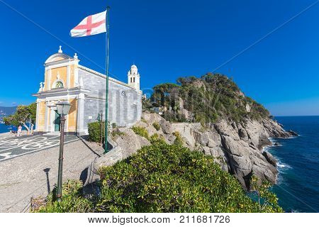 PORTOFINO, ITALY. October 20, 2017: Church of San Giorgio (Portofino). The church of San Giorgio is a Catholic worship site in Portofino, located on the San Giorgio slope. Rocky coastline and waves.