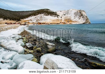 Waves and splash on Lake Baikal with rocks and trees near Uzuri village. Russia, Siberia