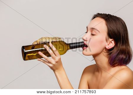 The girl sipped a bottle of wine on which the lizard on a gray background