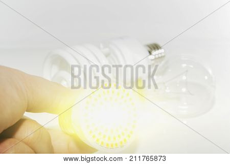 Several different led bulbs and compact fluorescent lamps and the male hand on a light background