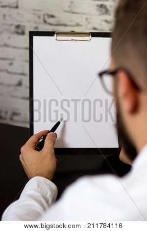 men looking and pointing with pen on a clipboard blank white paper in an office