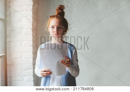 young hipster student woman or creative freelance designer working on project. Holding coursework or business plan.