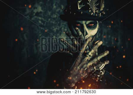 Close-up portrait of a man with a skull makeup dressed in a tail-coat and a top-hat. Baron Saturday. Baron Samedi. Dia de los muertos. Day of The Dead. Halloween.