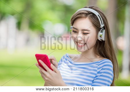 woman smile happily and use phone listen music in the park