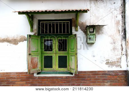 Old windows and an electric meter on a wall in kotagede