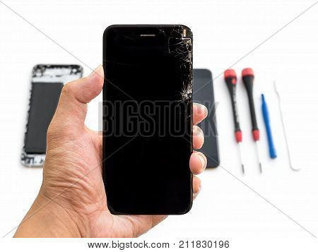Close-up of cracked smartphone screen in technician hand on blurred smartphone component background