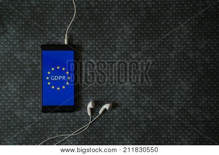 General Data Protection Regulation (GDPR) on smartphone and earphones placed on metal plate