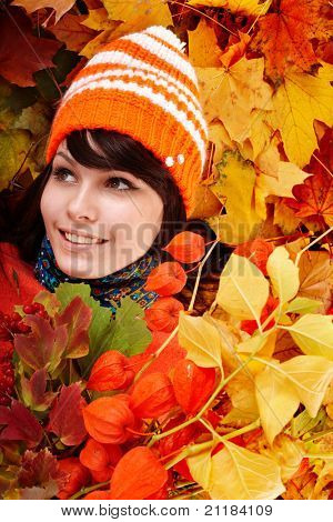 Mädchen im Herbst orange Hut auf Blatt-Gruppe mit Blumen. im Freien.