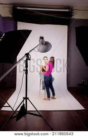 Professional make up artist doing maquillage for bald model in photo studio. Preparing for photo session
