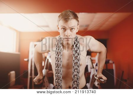 Close-up of guy engaged on uneven bars crossbar with chains in gym. Concept workout lifting