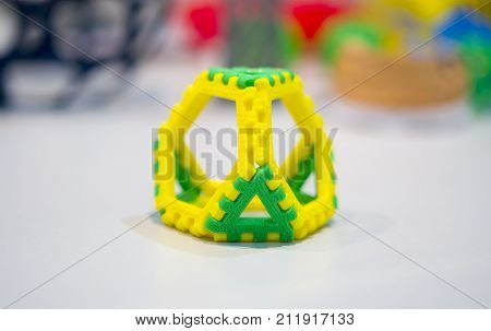 Abstract object of a yellow green color printed on a 3d printer on a white table. Fused deposition modeling, FDM. Progressive modern additive technology. Concept of 4.0 industrial revolution