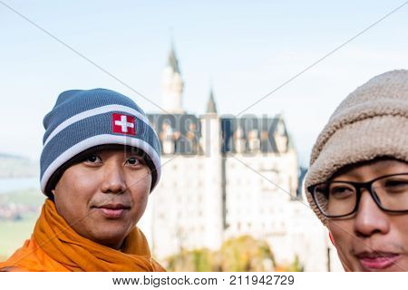 Schwangau, Germany - October 31, 2017: Buddhist monks are visiting the world-famous Neuschwanstein Castle, the 19th century Romanesque Revival palace built for King Ludwig II, with scenic mountain landscape in southwest Bavaria, Germany.