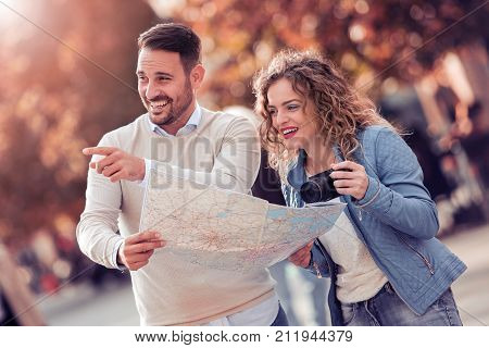 Loving couple with a map looking for an address on the strreet.