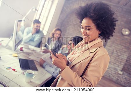 Portrait of confident young businesswoman using digital tablet while colleagues working in background.