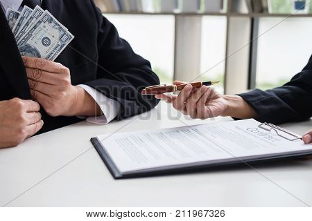 Bribery and corruption concept bribe in the form of dollar bills Businessman giving money while making deal to agreement a real estate contract and financial corporate.
