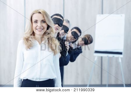 Friendly atmosphere. Young collective wearing black masks and bowing heads while standing in one line on the background