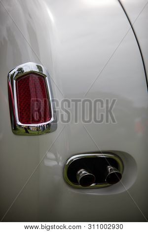 Close Up Vertical Image Of The Red Tail Light And Exhaust Pipes Of A White Classical Vintage Car.