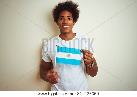 Afro american tourist man holding Argentinian Argentina flag over isolated white background with a happy face standing and smiling with a confident smile showing teeth