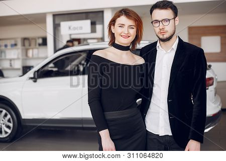 Stylish And Elegant Couple In A Car Salon