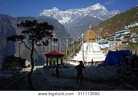 Namche Bazaar, Nepal - May 11, 2019: Every day life near Buddhist white stupa with view over Kongde mountain, Sagarmatha national park, Khumbu valley, Himalayas