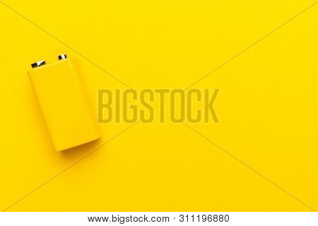 Blank Nine-volt Battery On The Yellow Background With Copy Space. Top View Of Yellow Nine-volt Batte
