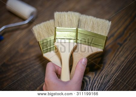 Painting Tools In Hand. Craft Wooden Background. New Brushes