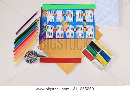 Back To School, Assortment Of Colored Pencils, Pens And Rulers And The Multiplication Table On A Lig