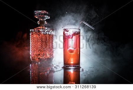 Cocktail Glass Splashing On Dark Toned Smoky Background Or Colorful Cocktail In Glass. Party Club En