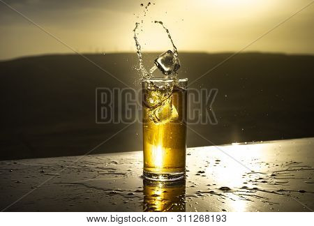Cooling Summer Drink Concept. Cocktail Glasses Splashing On Sunset. Close Up Wet Glass Of Cold Drink