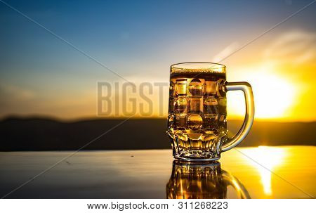 Glass Of Beer On A Beach At Sunset. Cooling Summer Drink Concept. Close Up Of A Glass Of Draught Bee