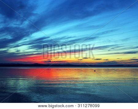 Multi-colored Blue And Orange Sunset Sky Over The Lake, A Fantastic Picture Of Clouds, Reflections O