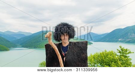Georgian Man In A Beech Costume On A Background Of Mountains. Selective Focus.