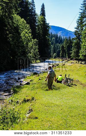 Iezer Mountains - Romania - 2019. People Relaxing Next To A River, And Having Barbeque.