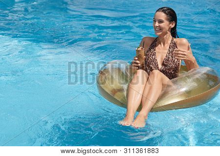 Summer And Recreation Concept. Attractive Woman Sitting On Big Rubber Ring In Middle Of Swimming Poo