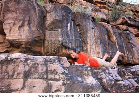 Young Woman Hiker Avoids A Bat On A Narrow Rock Ledge Above Hance Creek In Grand Canyon National Par