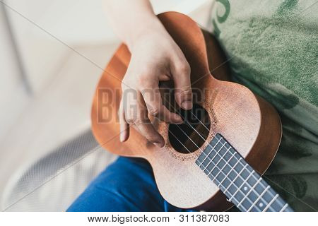 Ukulele Game. A Man Playing A Little Guitar. The Performer Writes The Music On The Ukulele At Home.