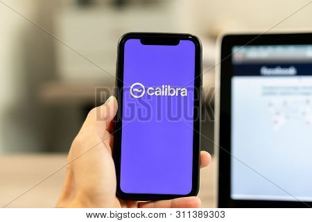 12 July 2019, Ljubljana Slovenia - Hand Holding Smartphone With Calibra Logo Next To Facebook Webpag