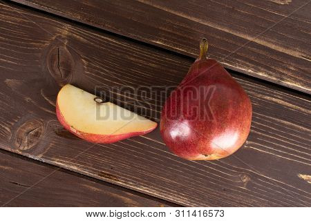 Group Of One Whole One Slice Of Fresh Dark Red Pear Anjou Flatlay On Brown Wood