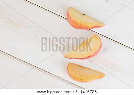 Group Of Three Slices Of Fresh Dark Red Pear Anjou Flatlay On White Wood