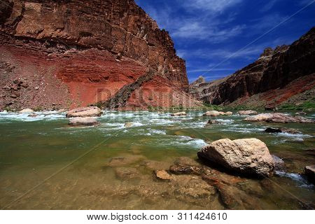 Hance Rapids In Grand Canyon National Park, Arizona, With Red Canyon Walls Under A Deep Blue Sky.