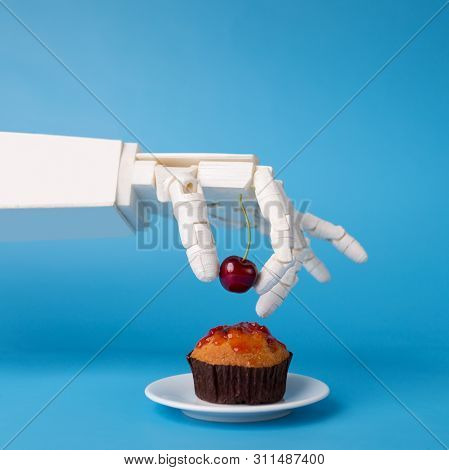 Chef Robotic Assistant In Kitchen Technology. Robot Hand Decorating Sweet Cupcake With Fresh Cherry,