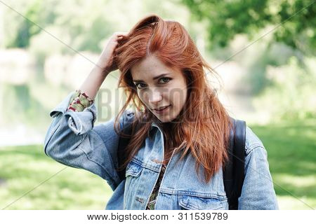 Young Woman Wearing Denim Jacket Playing With Her Hair And Giving A Coy Look - Authentic Real People