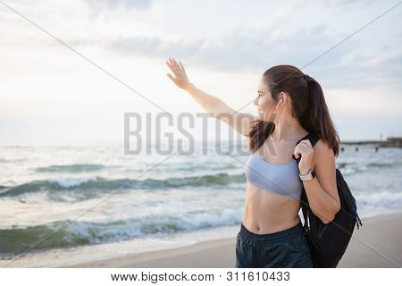 Young Brunette Woman With Wireless Earbuds, Smart Watches And Black Backpack Resting After Morning W