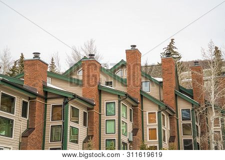 Homes With White Wall Sidings And Red Brick Chimneys Against Cloudy Sky