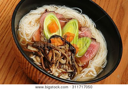 Japanese Food Udon With Noodles And Meat In A Dark Bowl On A Wooden Background