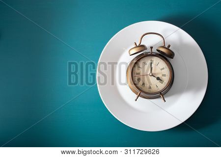 concept of intermittent fasting, ketogenic diet, weight loss. alarmclock on a plate