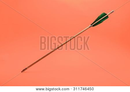 Old Green Wooden Arrow On A Beautiful Peach Background.