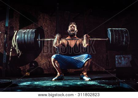 Muscular Bearded Tattoed Fitness Man Doing Deadlift A Barbell Over His Head In Modern Fitness Center